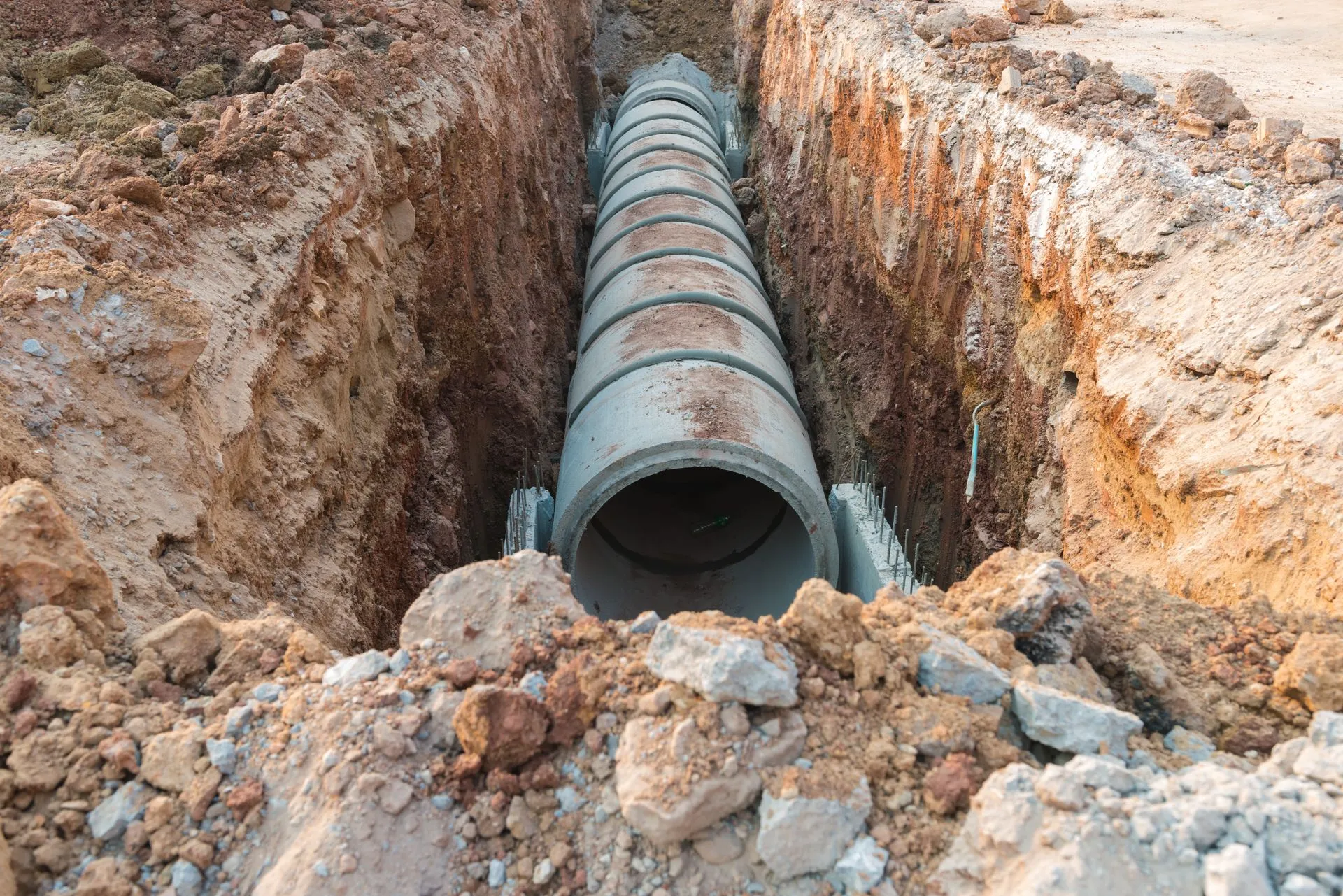 A large concrete pipe is being installed in a trench.